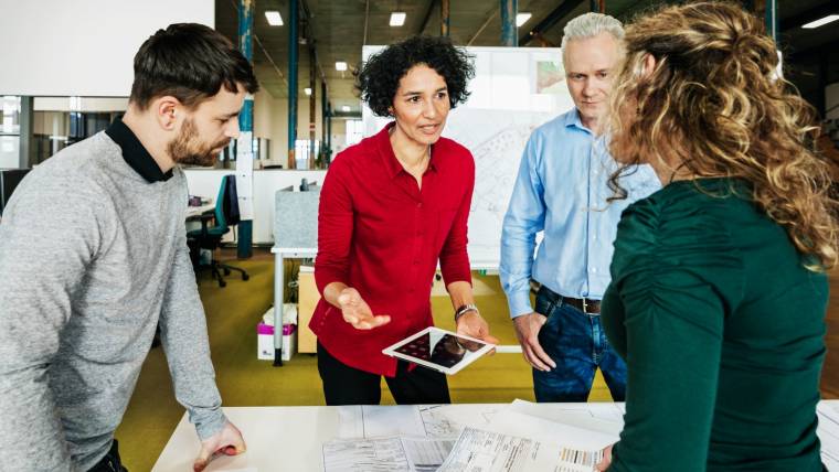 Business woman talking to employees around a table