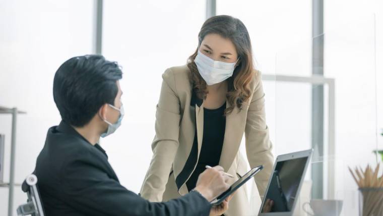 Two masked workers discuss business