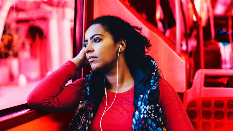 a woman on a bus wears headphones and gazes out the window