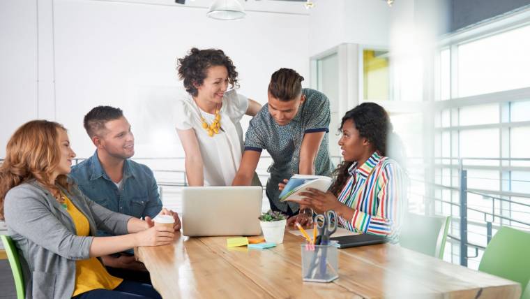 Five workers smiling around a conference table