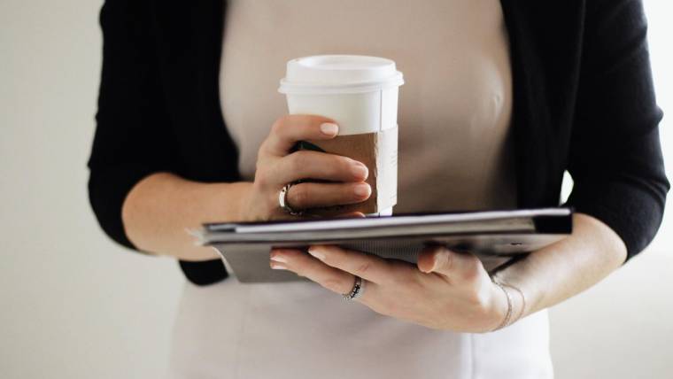 A woman holding coffee and a laptop