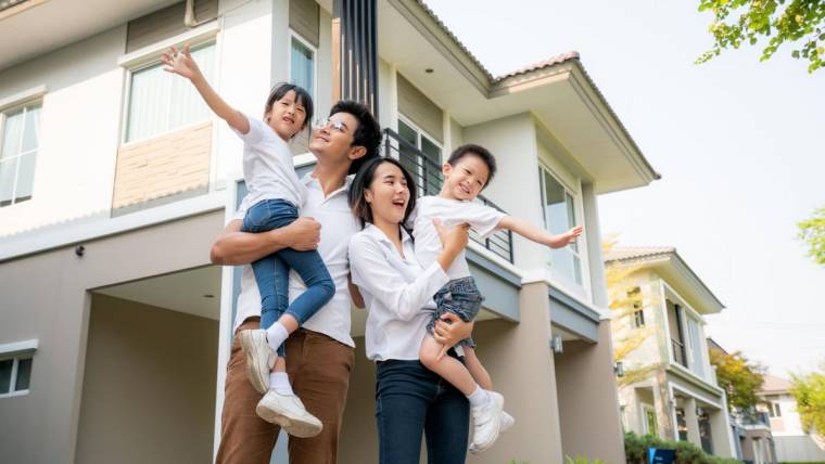 A family smiles in front of their home