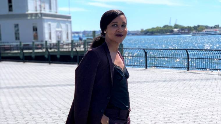 A business woman stands by a river in a city