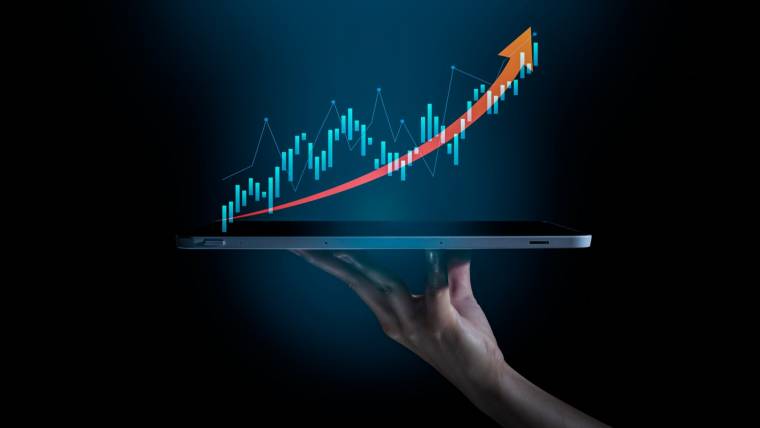 A hand holding a tablet with a graph showing upward movement