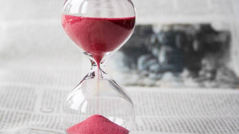 an hourglass with pink sand shows more than half of the allotted time is remaining