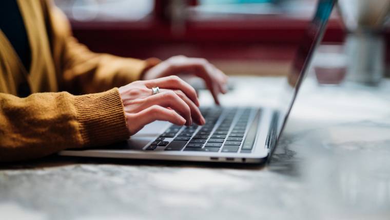 A person's hands typing on a laptop