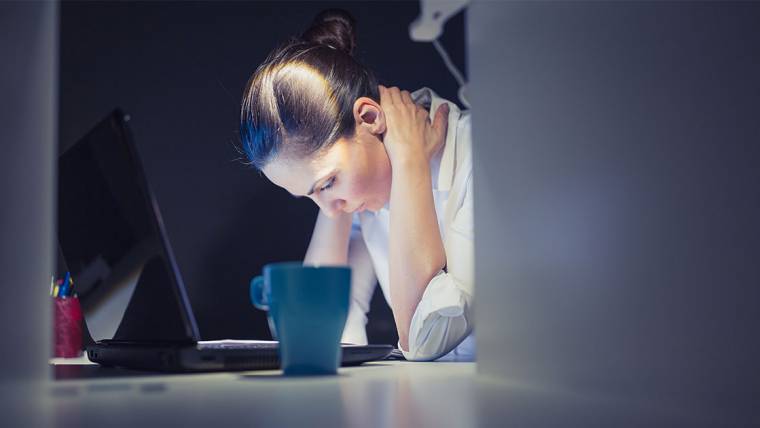 A stressed woman looks down at her laptop