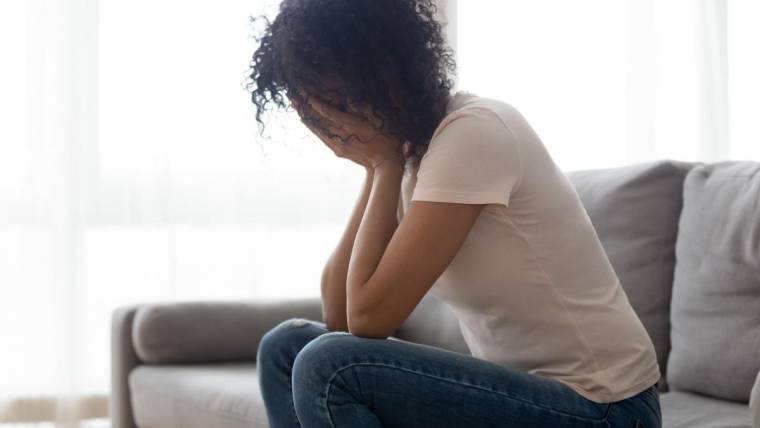 A woman holds her hands over her face