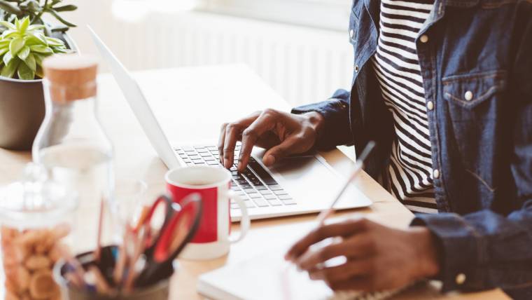 Person working at a laptop and writing