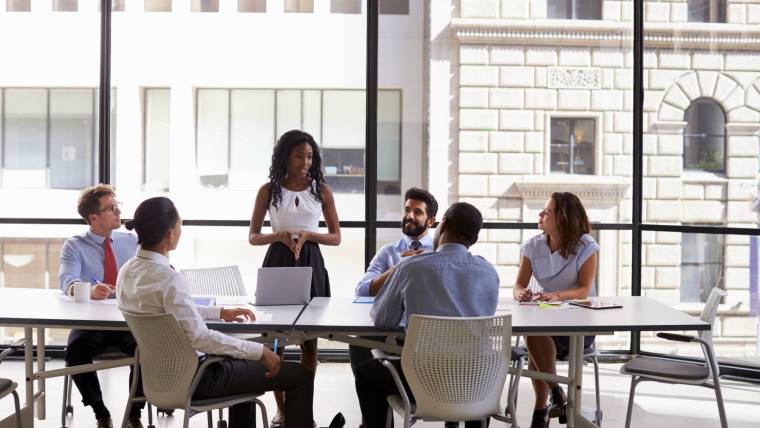 A business woman stands by a conference table