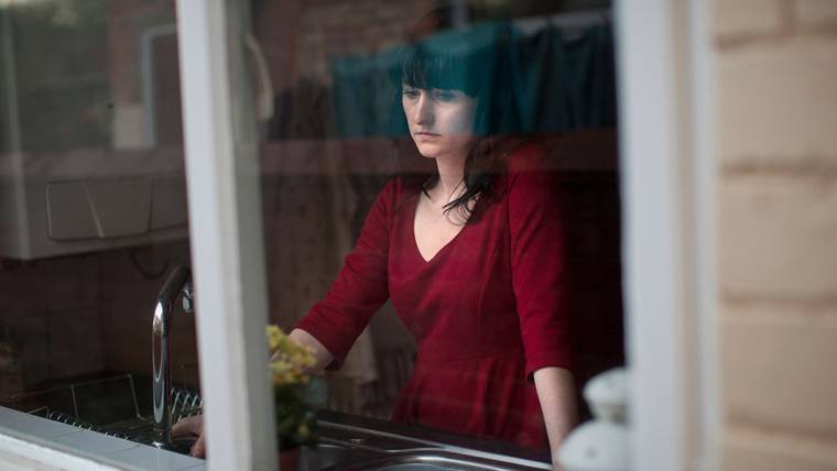 depressed woman standing in a kitchen