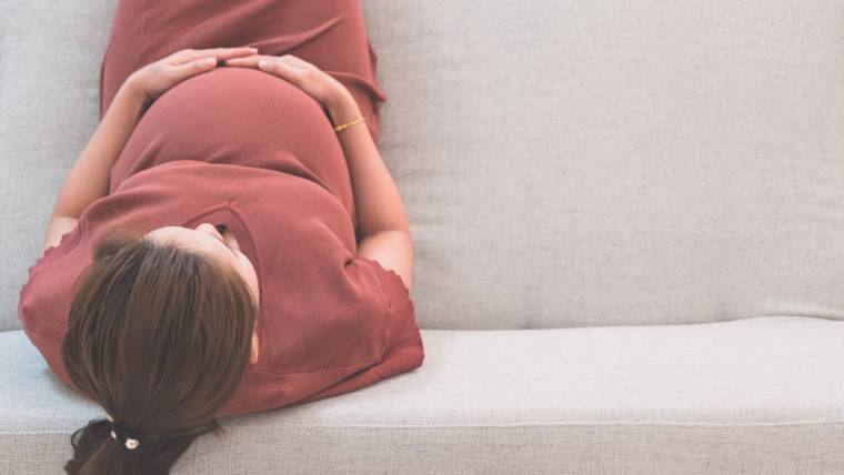 A pregnant woman gazes down at her stomach