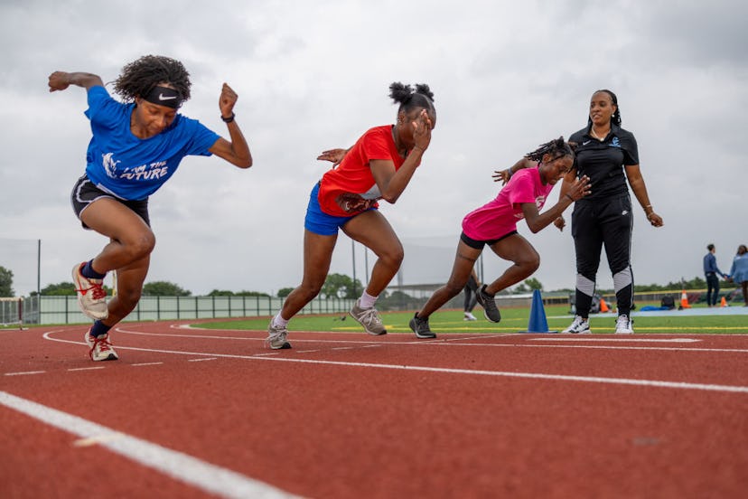 High school track athletes taking off from the starting line while their coach looks on, in a story ...