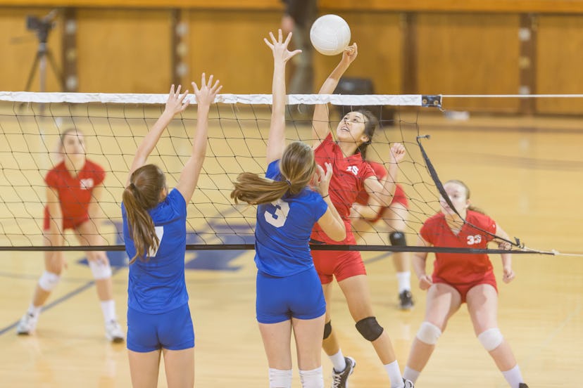 High school female volleyball player spiking the ball during a competitive game, in a story about sp...